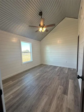 an empty room with wooden floor chandelier fan and windows
