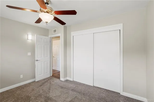 an empty room with closet and a chandelier fan