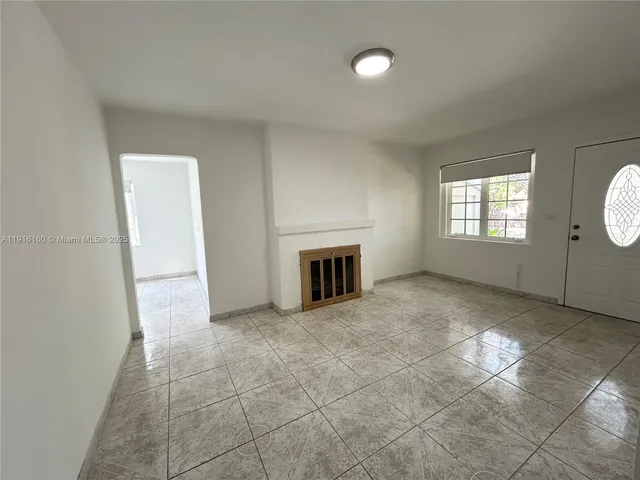 an empty room with windows and fireplace