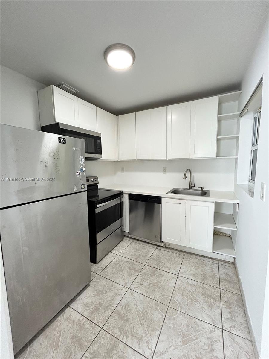 40 Northwest 39th Street, Unit 40 Miami, FL 33127 - Photo 7 of 17 a kitchen with a stove a refrigerator and white cabinets