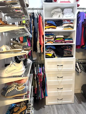 a view of walk in closet with clothes and shoes