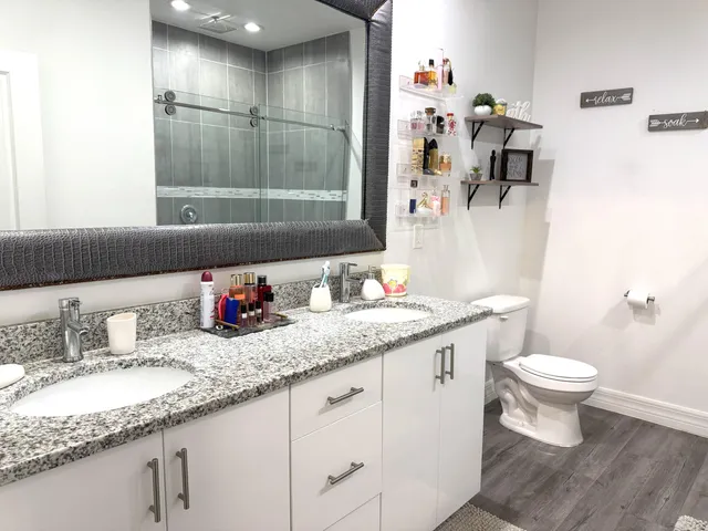 a bathroom with a granite countertop sink a toilet and a mirror