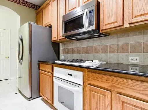 a kitchen with stainless steel appliances granite countertop a refrigerator and a stove top oven