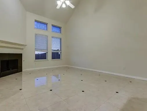 an empty room with a fireplace and chandelier fan