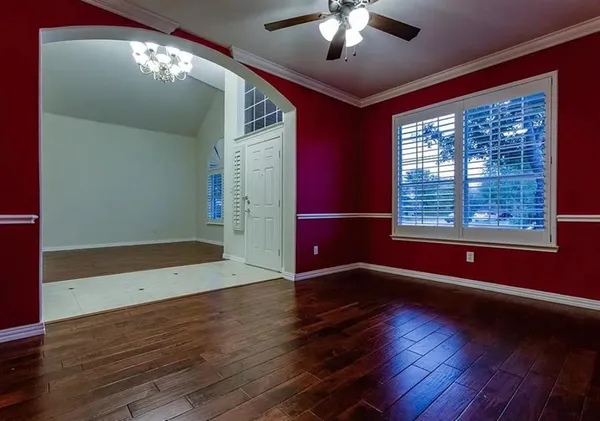 an empty room with wooden floor fan and windows