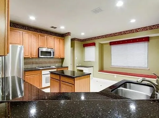 a kitchen with stainless steel appliances granite countertop a sink a stove and a refrigerator
