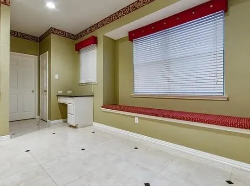 a view of an empty room with a window and a kitchen