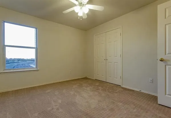 an empty room with a window and a chandelier fan