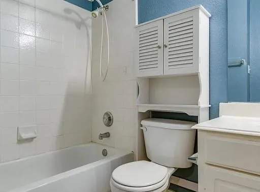 a bathroom with a granite countertop toilet a sink and a bathtub