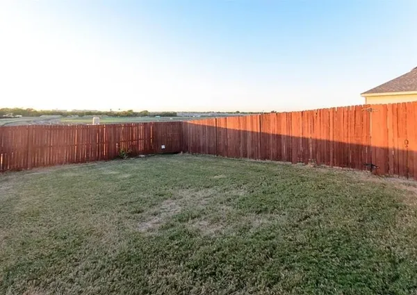 a view of backyard with wooden fence