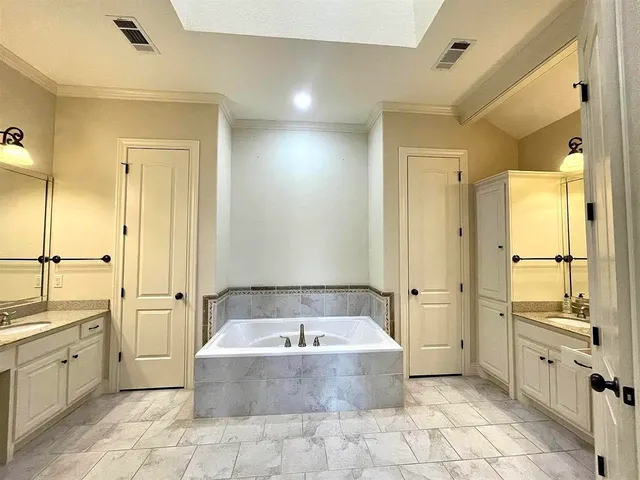 a bathroom with a granite countertop tub sink shower and mirror