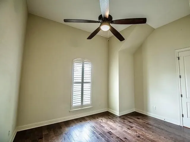an empty room with wooden floor closet and windows