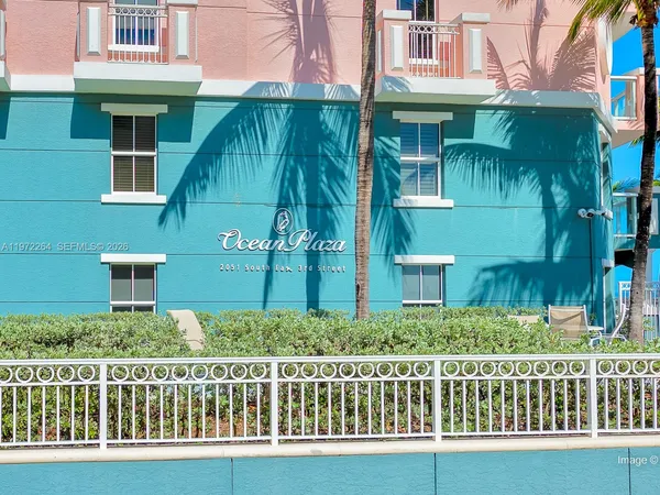 a view of a street with a building and palm trees