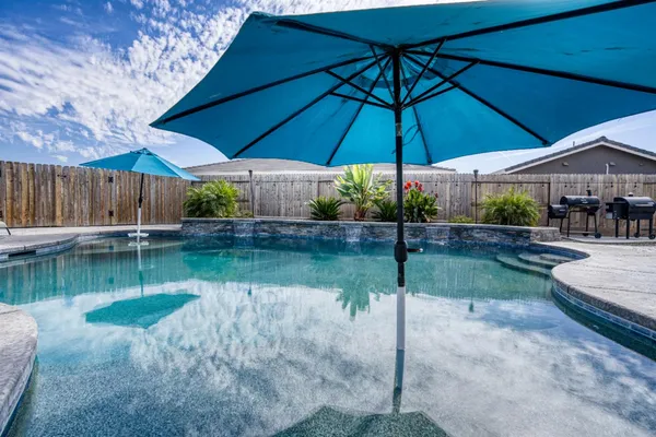 a backyard of a house with table and chairs under an umbrella