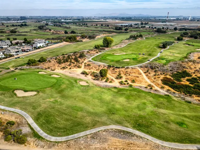 a backyard of a house with table and chairs under an umbrella