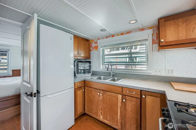 a utility room with stainless steel appliances white cabinets and a window