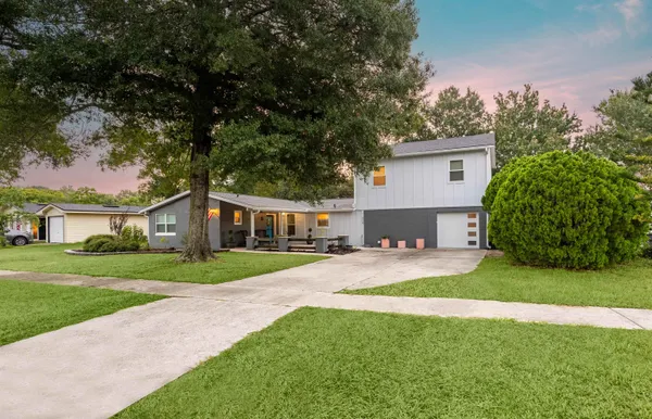 a front view of a house with a yard and trees