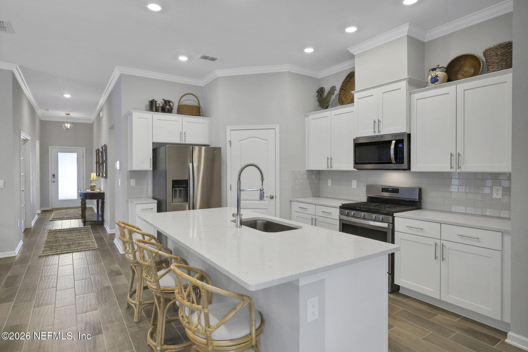 84 Cardinal Branch Lane St. Augustine, FL 32095 - Photo 10 of 45 a kitchen with stainless steel appliances kitchen island granite countertop a stove a sink a refrigerator and white cabinets with wooden floor