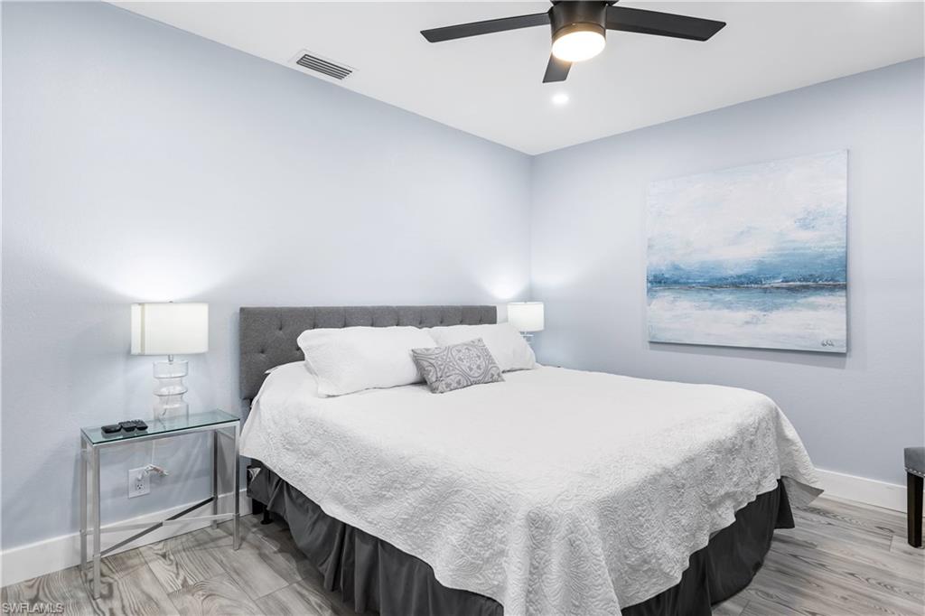 940 3rd Street South, Unit 204 Naples, FL 34102 - Photo 12 of 25 a bedroom with a bed and a chandelier