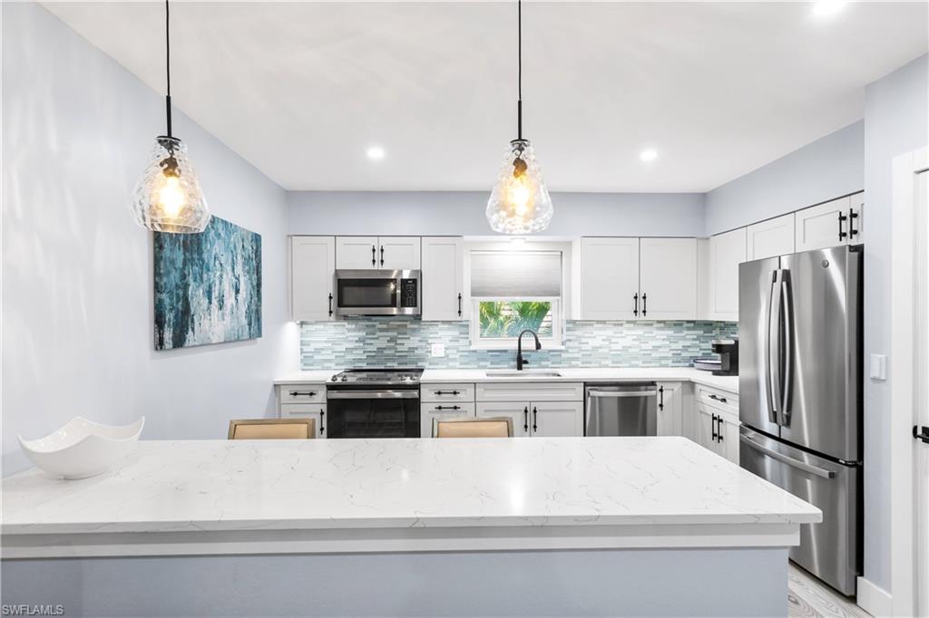 940 3rd Street South, Unit 204 Naples, FL 34102 - Photo 3 of 25 a kitchen with kitchen island granite countertop a sink stove and refrigerator