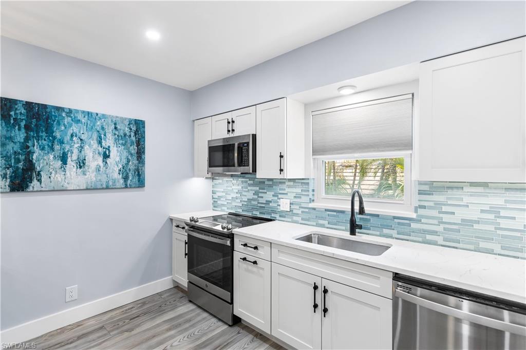 940 3rd Street South, Unit 204 Naples, FL 34102 - Photo 5 of 25 a kitchen with stainless steel appliances granite countertop a sink a stove a microwave a counter space and cabinets