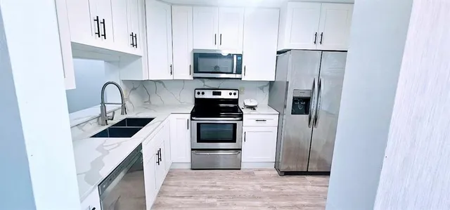a kitchen with a refrigerator sink and cabinets