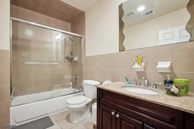 a bathroom with a granite countertop bathtub shower sink vanity and toilet