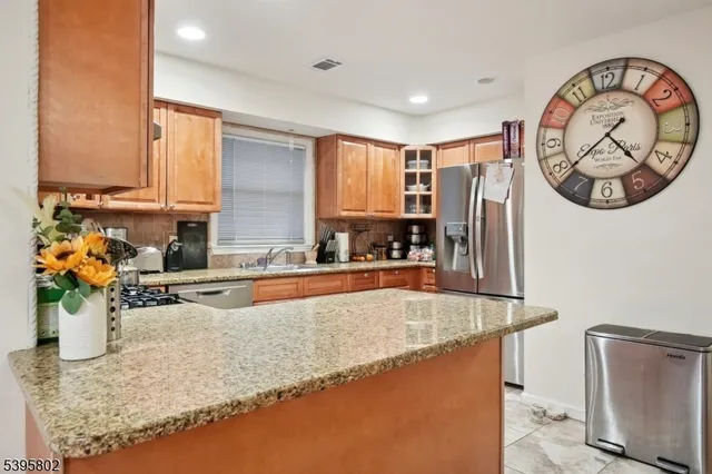 a kitchen with stainless steel appliances granite countertop a sink a stove top oven a chimney and a refrigerator