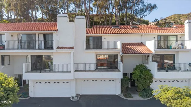 a view of a white house with large windows and a potted plant