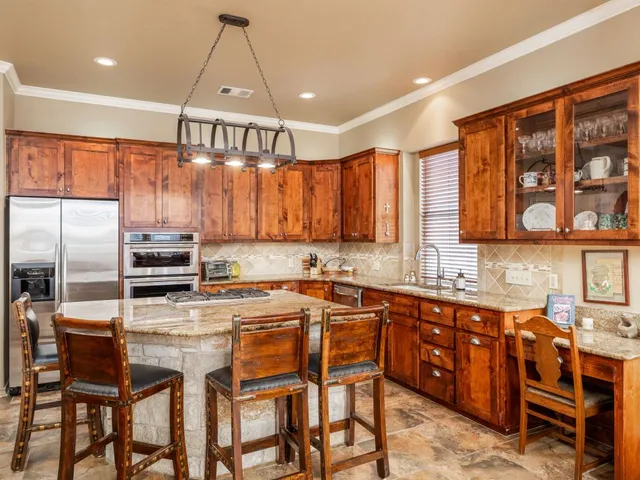a kitchen with stainless steel appliances a table chairs refrigerator and cabinets