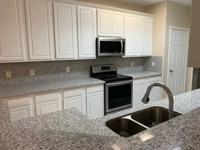 a kitchen with granite countertop white cabinets and sink