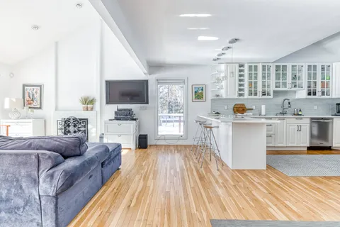 a living room with stainless steel appliances kitchen island granite countertop a couch and wooden floor