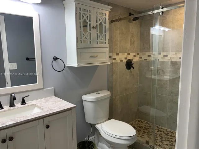 a bathroom with a granite countertop sink toilet and shower