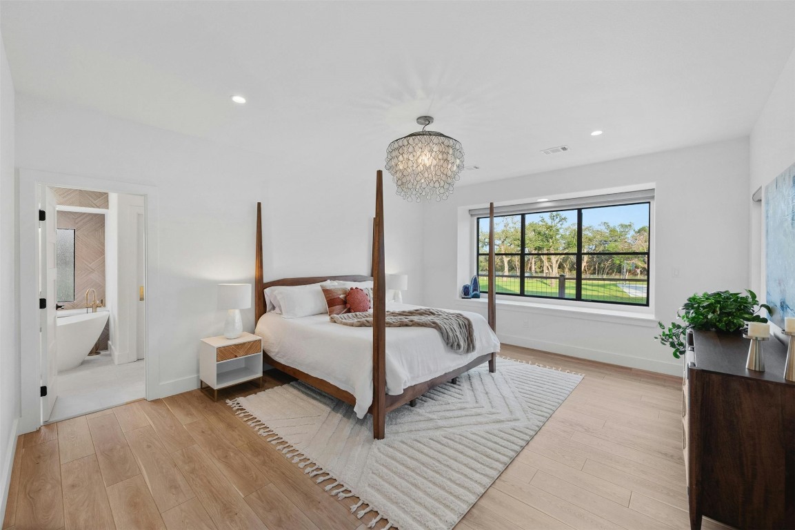 333 Stallion Lane Dripping Springs, TX 78620 - Photo 14 of 40 a spacious bedroom with a bed and a chandelier