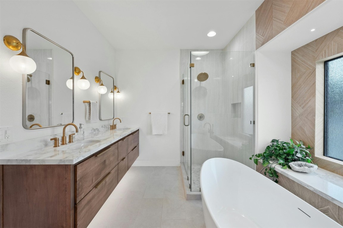 333 Stallion Lane Dripping Springs, TX 78620 - Photo 16 of 40 a spacious bathroom with a double vanity sink a large mirror a bathtub and shower