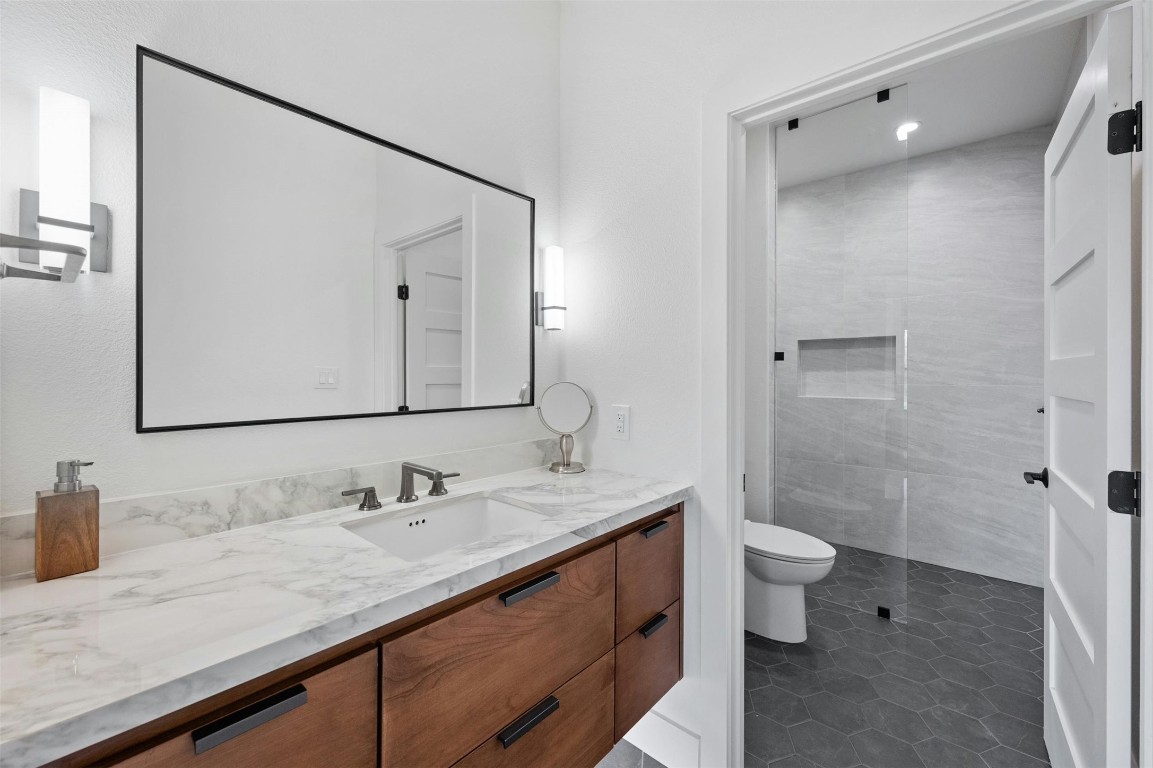 333 Stallion Lane Dripping Springs, TX 78620 - Photo 19 of 40 a bathroom with a granite countertop sink toilet and shower