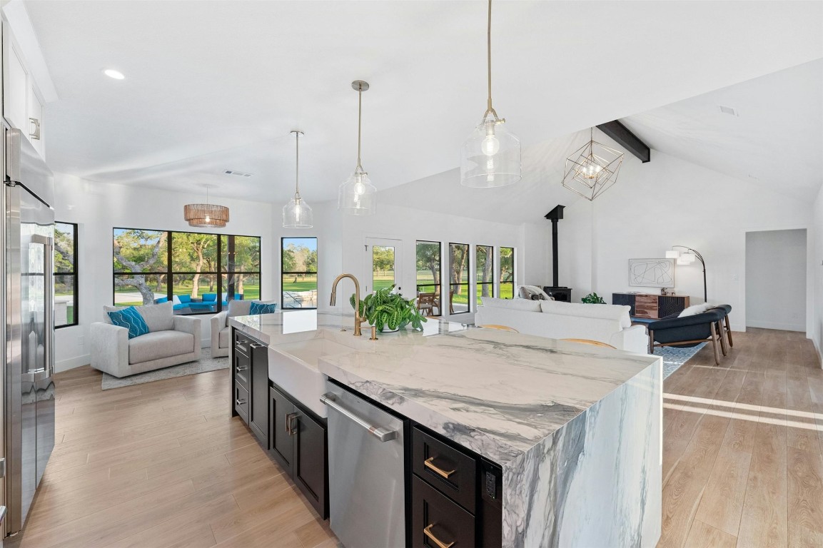 333 Stallion Lane Dripping Springs, TX 78620 - Photo 40 of 40 a kitchen with granite countertop a stove a sink a dining table and chairs with wooden floor