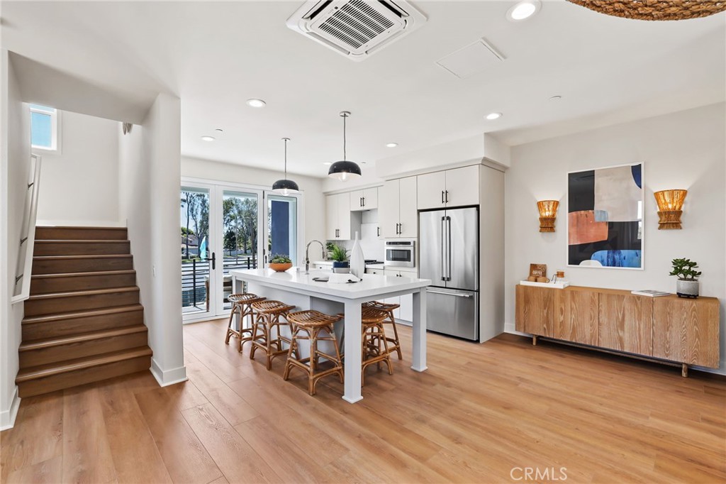 19071 Main Street, Unit 105 Huntington Beach, CA 92648 - Photo 6 of 18 a kitchen with kitchen island wooden floors stainless steel appliances and sink