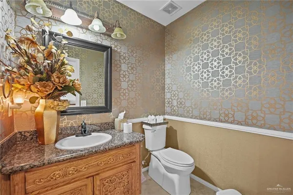 a bathroom with a granite countertop sink mirror vanity and toilet