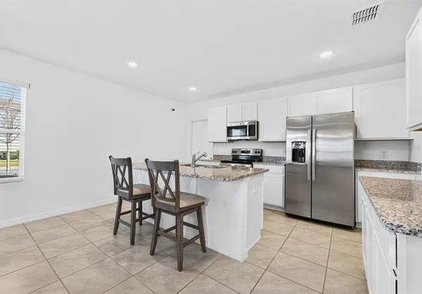 a kitchen with a refrigerator a table and chairs in it