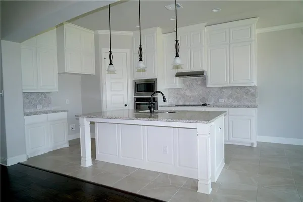 a kitchen with stainless steel appliances granite countertop a sink a stove and white cabinets