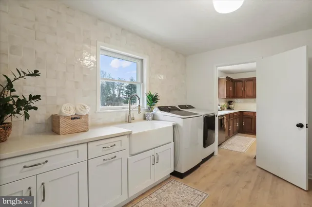 a kitchen with a sink dishwasher and white cabinets with wooden floor