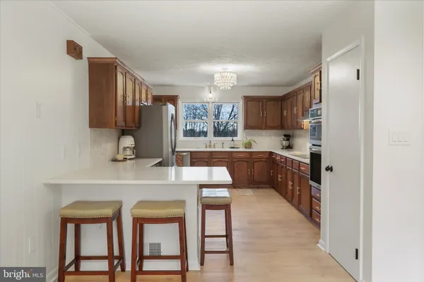 a kitchen with stainless steel appliances granite countertop a sink dishwasher stove and refrigerator with wooden cabinets