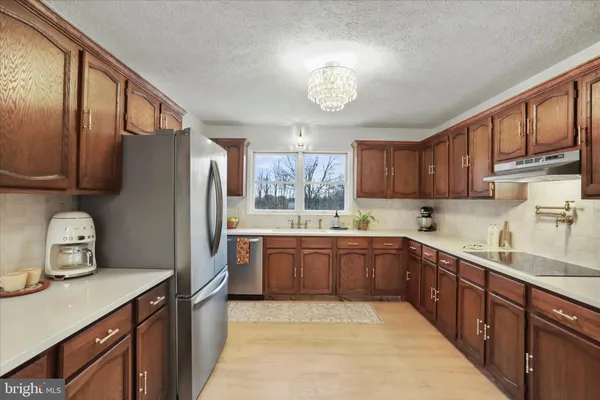 a kitchen with stainless steel appliances granite countertop wooden cabinets a sink and dishwasher with wooden floor