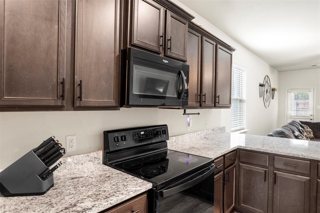 105 Patton Lane Venus, TX 76084 - Photo 28 of 29 Kitchen with dark brown cabinetry, black appliances, light stone countertops, and open floor plan