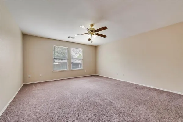 an empty room with windows and fan