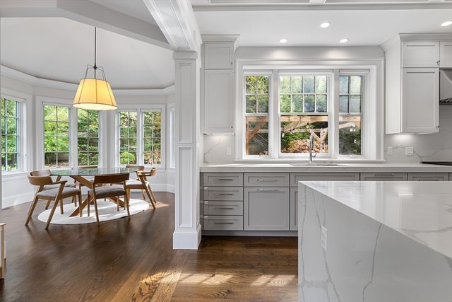 a dining room with wooden floor a chandelier a flat screen tv and windows