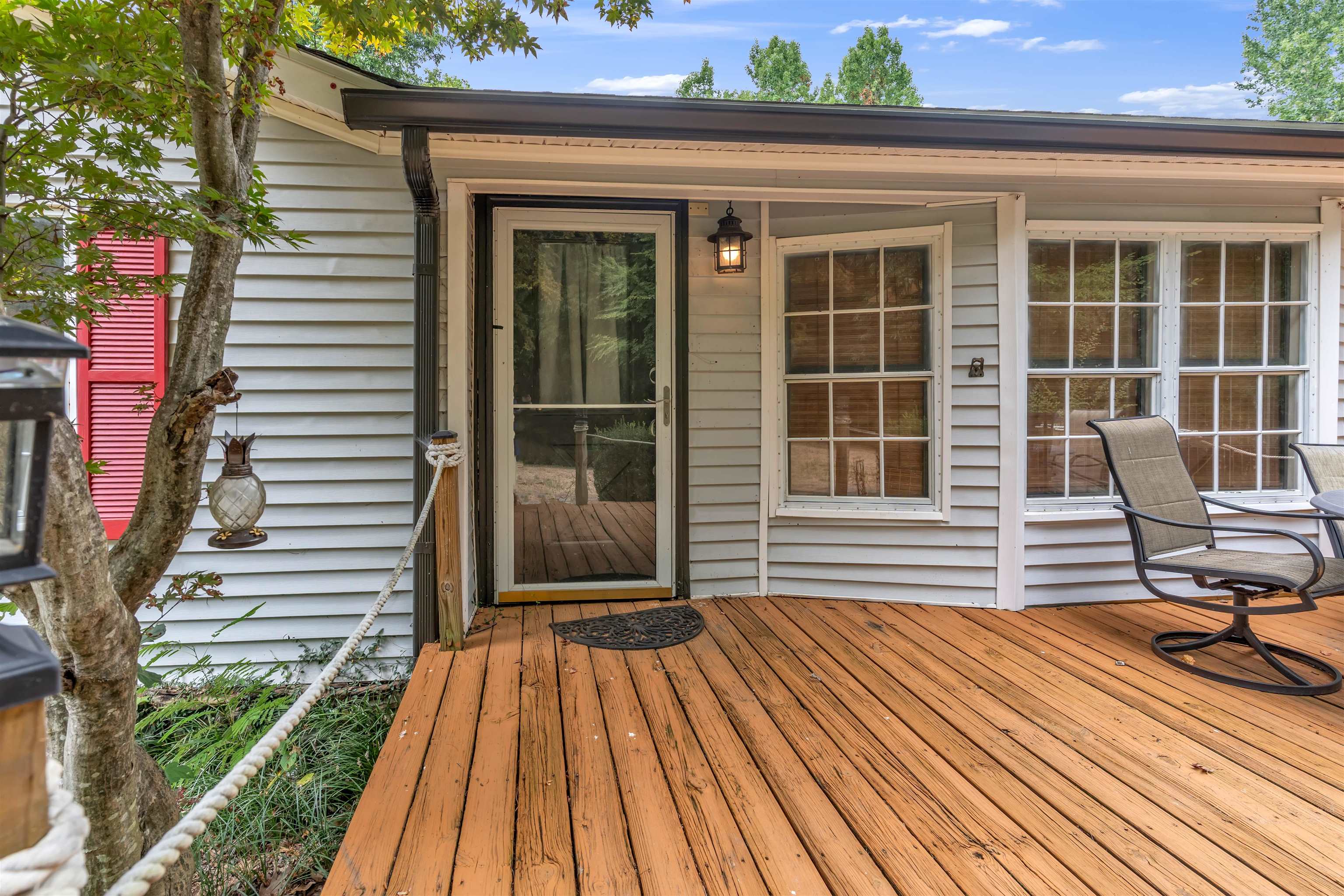 Expansive wood deck with a clear glass storm door and exterior wall sconce
