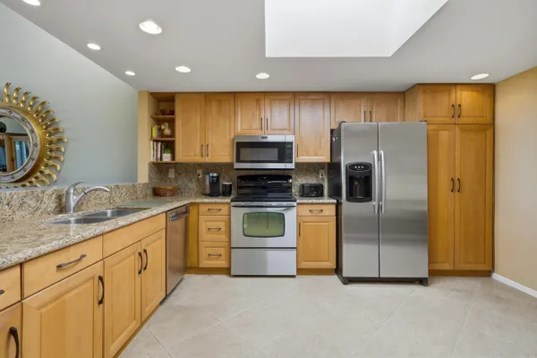 a kitchen with stainless steel appliances granite countertop a refrigerator a stove and a sink with wooden floor