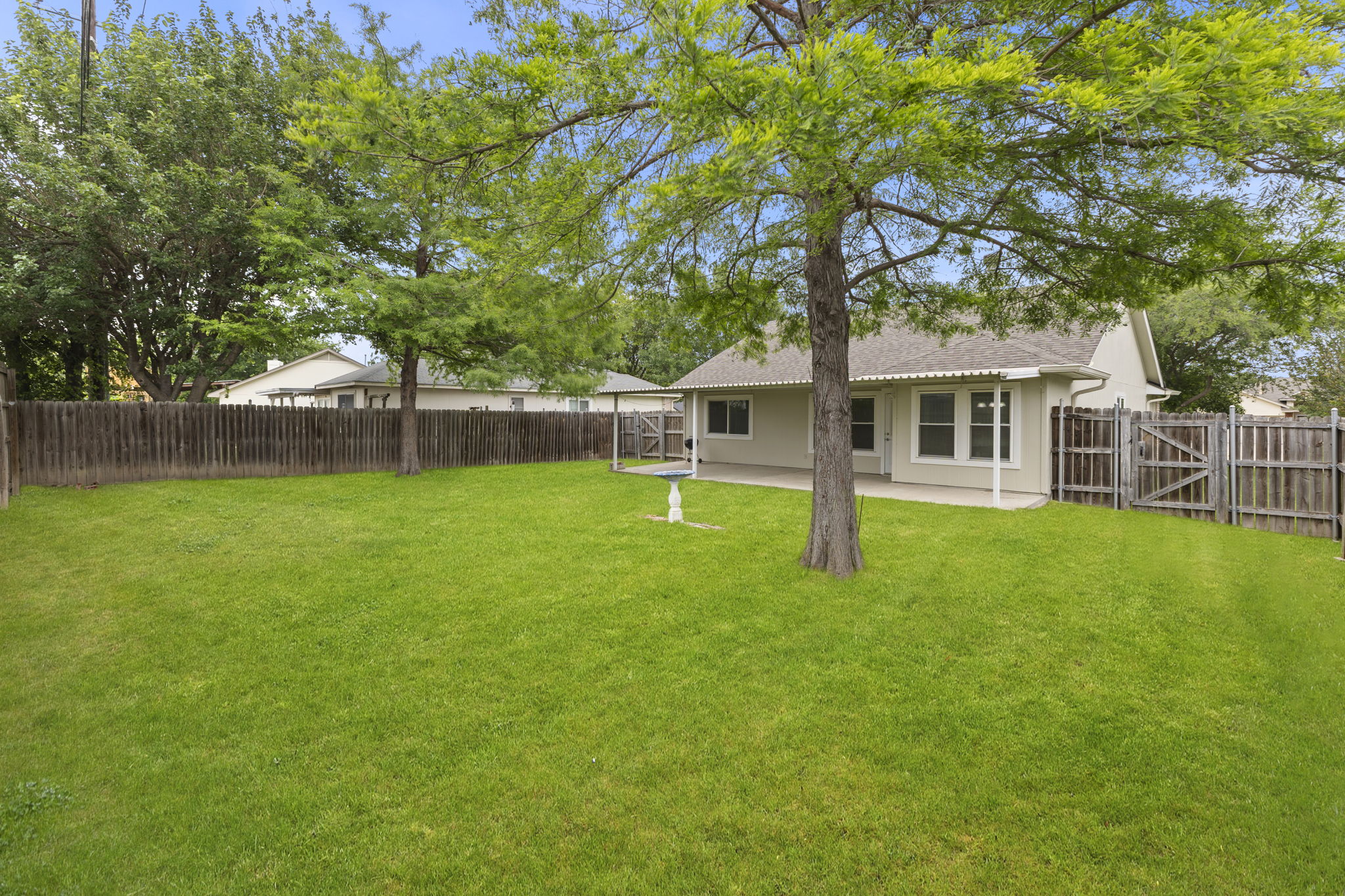 290 Bailey Loop Kyle, TX 78640 - Photo 30 of 33 Expansive backyard featuring a large green lawn, mature trees, and a full privacy fence